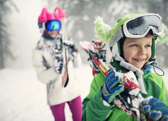 Little skiers carrying skis on a winter day